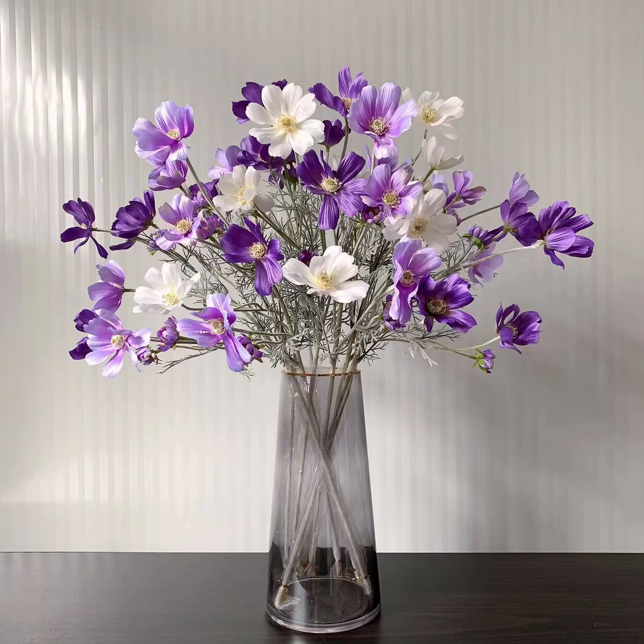 Artificial chamomile bouquet with white and purple flowers in a glass vase