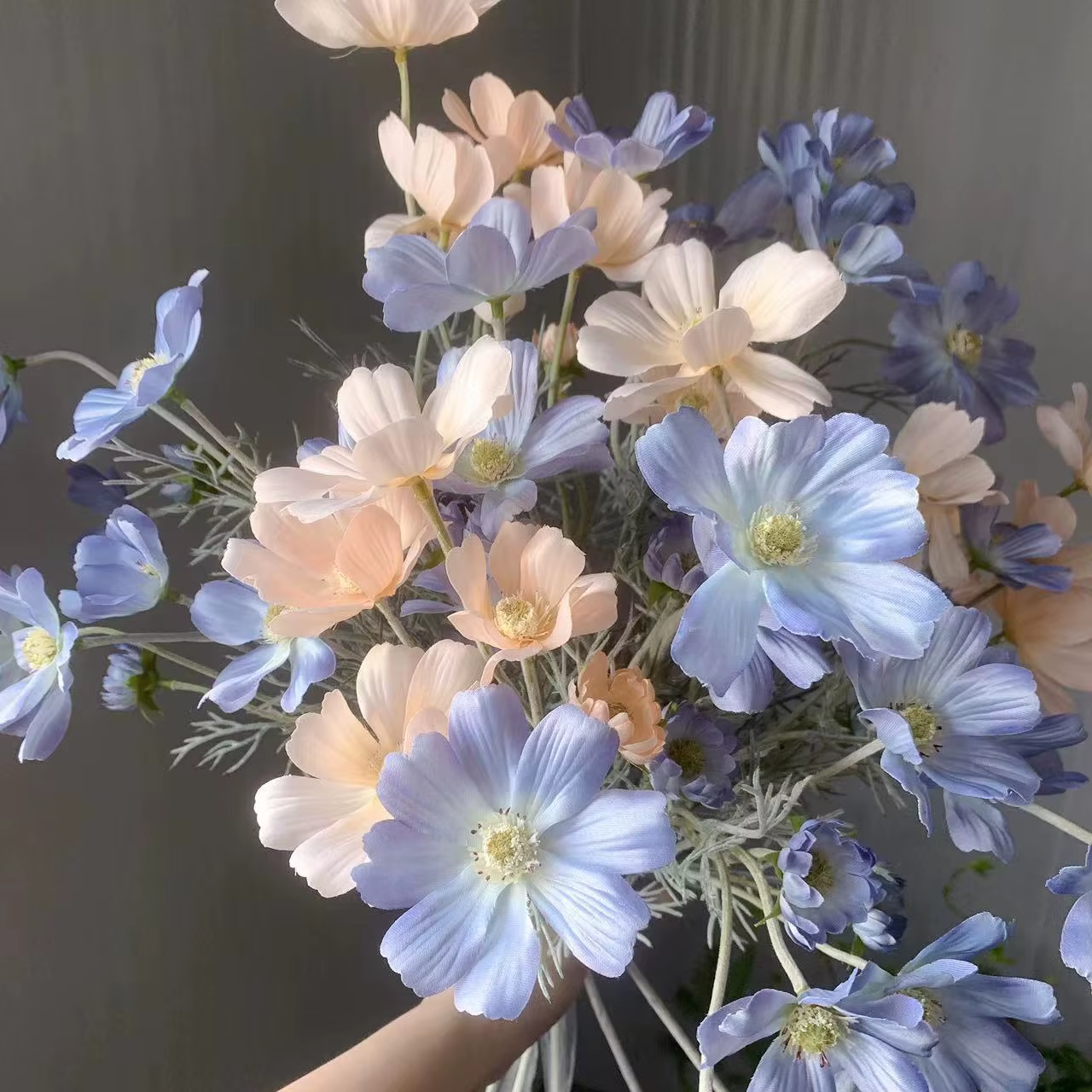 Close-up of artificial chamomile flowers in light blue and peach colors